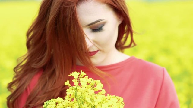 Happy girl smiling on camera with bouquet of rape blossom. Slow motion