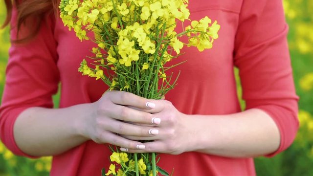 Pretty girl with rape bouquet on field backgrount. Slow motion