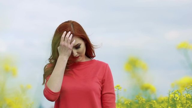 Girl in the rape field and sky horizon smiling to the camera, wind blow. Slowly