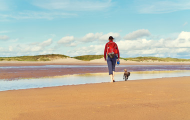 A woman walking alone a deserted beach.