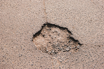 Crack in asphalt. Damaged pavement. Poor condition of the road surface.