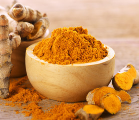 Turmeric  powder in  wooden bowl on wooden