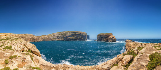 Sunny wide panoramic view of rocky Dweira bay in Gozo, Malta.