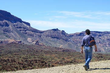 Fototapeta na wymiar Man with his backpack walking on volcanic mountains of Tenerife. Concept for travel o tourism
