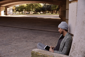 Modern young man with tablet pc under a bridge