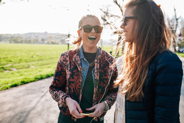 Two girls walking in the park and listening to music.