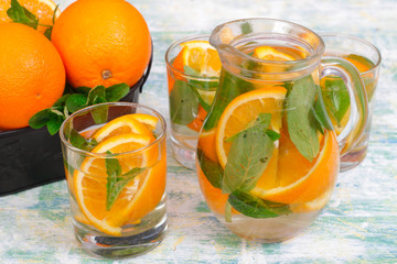 Lemonade with oranges and mint on a light wooden background. Mojito
