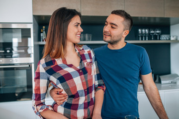 Young couple standing in the kithcen. They are hugging.
