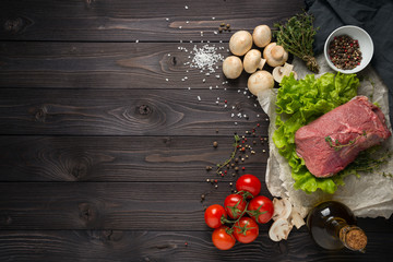 raw meat with ingredients on a wooden background