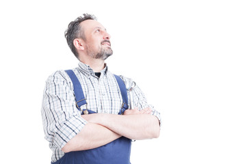 Confident handsome mechanic holding arms crossed and looking up