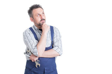 Portrait of young pensive mechanic in overalls looking up - obrazy, fototapety, plakaty