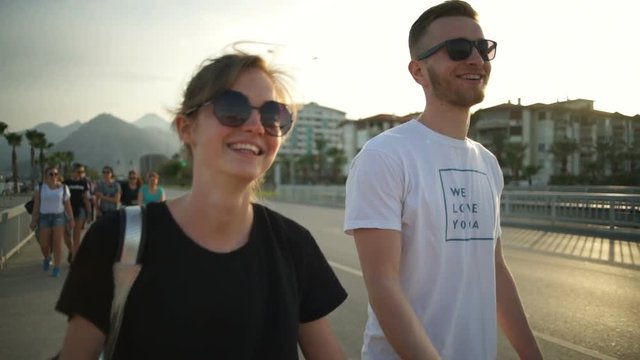 young smiling couple walking along the road slow motion