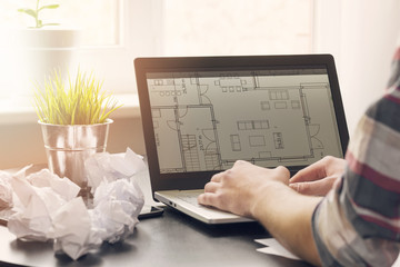 architect, interior designer working on laptop with floor plans