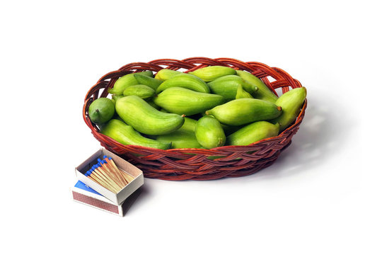 small basket with many small green unripe fruits of caigua appropriate for the marinating on white background with matchbox and matches