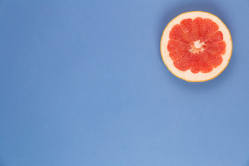 Photo kinds of pop art. Grapefruit on a blue paper texture background in the upper right corner
