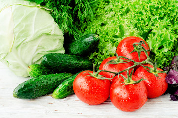 
Fresh juicy ripe summer useful vegetables and greens, red tomatoes , cucumbers , cabbage , lettuce , basil , parsley , dill and salt and spices on a wooden background