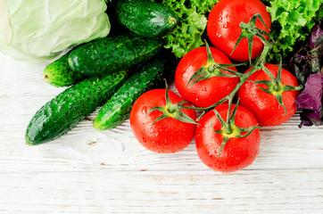 
Fresh juicy ripe summer useful vegetables and greens, red tomatoes , cucumbers , cabbage , lettuce , basil , parsley , dill and salt and spices on a wooden background