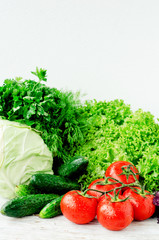 
Fresh juicy ripe summer useful vegetables and greens, red tomatoes , cucumbers , cabbage , lettuce , basil , parsley , dill and salt and spices on a wooden background