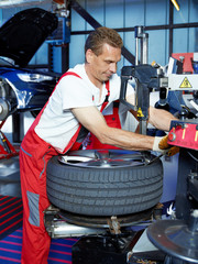 Fototapeta premium Car mechanic with tyre lever is fitting a tyre