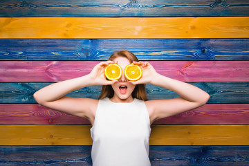 Fruit fashion girl. Young girl holds half of a juicy orange. Surprised face. Young girl on a...