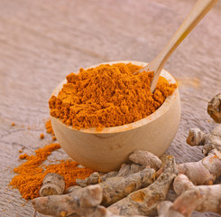 Turmeric roots powder in bowl wooden