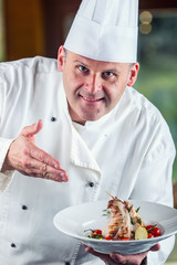 Chef. Chef cooking.Chef decorating dish. Chef preparing a meal. Chef in hotel or restaurant kitchen prepares decorating dish with tweezers. Chef cooking, only hands. Decorate the rabbit thighs legs.