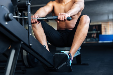 Fototapeta na wymiar Muscular fitness man using rowing machine