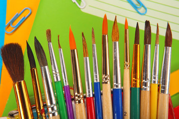 Paint brushes on exercise book background. Selective focus