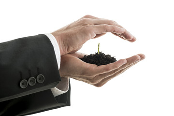 Closeup of businessman holding a pinch of fertile soil with gree