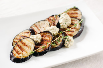 Grilled eggplants with paste on white plate. Close-up of grilled eggplants. Dish of grilled eggplant front view.
