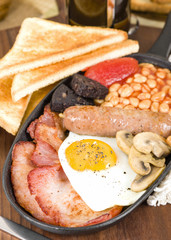 Full English Breakfast - Traditional English fry-up with egg, bacon, mushrooms, tomatoes, sausage, black pudding and baked beans. Served with slices of toast.