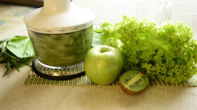 Cooking of green smoothie, cocktail in a blender. Still Life with a blender, fruit and herbs on the table. The concept of a healthy lifestyle