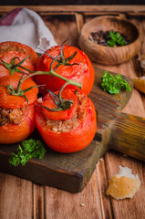 Baked stuffed chicken tomatoes served on cutting board  on wooden background. Selective focus