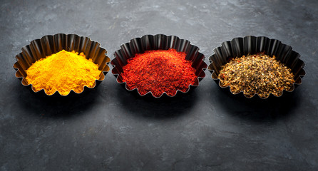 Spices turmeric powder, hot chili powder and herbs. Black grunge background