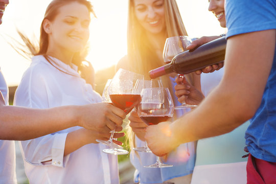 Group Of Happy Friends Having Red Wine On The Beach