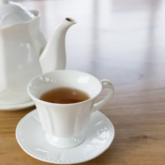 Hot black tea in white cup set on wooden table
