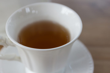Hot black tea in white cup set on wooden table