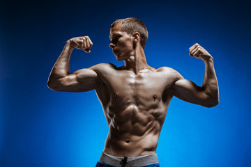 Fototapeta na wymiar Fit young man with beautiful torso on blue background