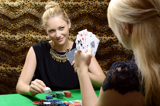 Frauen spielen Karten oder Poker an Pokertisch in Hinterzimmer