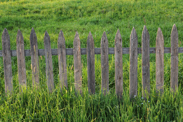 old wooden fence in green field with lush grass