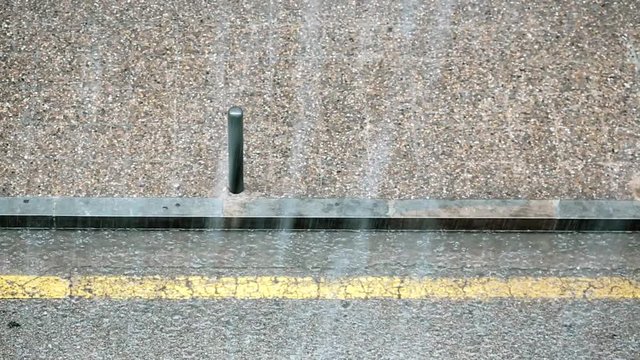 Rainstorm falling on an empty street with sidewalk