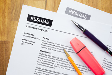 Top view of office desk with resume information, highlighter, pencil and pen