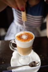 woman adds sugar in coffee