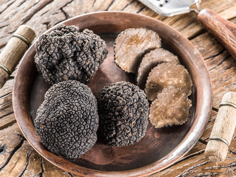 Black truffles on the plate on the old wooden table.