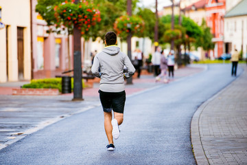 Young hipster man running in town, main street