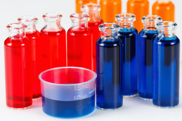 Blue, red and orange liquid in chemical lab test tubes on white background