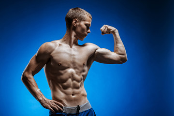 Fototapeta premium Fit young man with beautiful torso on blue background