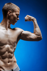 Fototapeta na wymiar Fit young man with beautiful torso on blue background