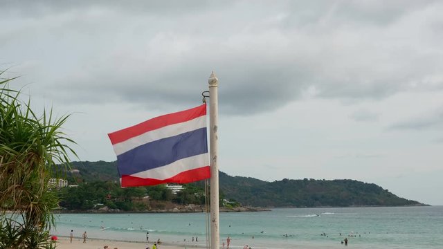 National Thailand Flag On The Cloudy Sky Background. Phuket, Kata Beach. Time Lapse