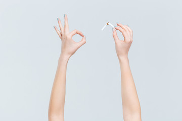Female hands holding broken cigarette and showing ok sign